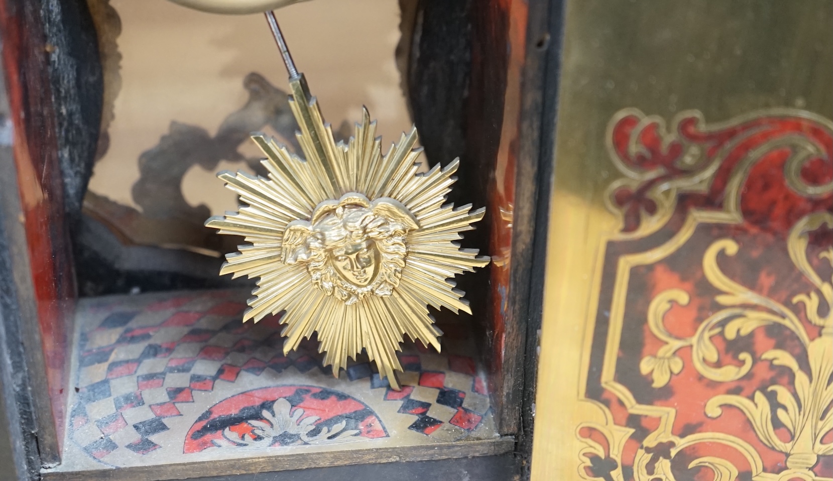 A French scarlet Boulle clock, and original bracket, the waisted case with glass front enclosing boulle interior and sunburst pendulum, c. 1860, clock 42cm high. Condition - fair, untested